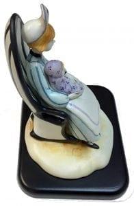 Nurse Figurine titled Loving Care is a P Buckley Moss figurine featuring a nurse holding a baby and giving comfort. Colors of lavender, blue, cream, golden for hair and black base and tiny cat. 