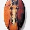 Horse porcelain pendant by P Buckley Moss to be worn with a gold colored jewelry surround featuring a horse head in shades of rust, cream, brown and black hues.