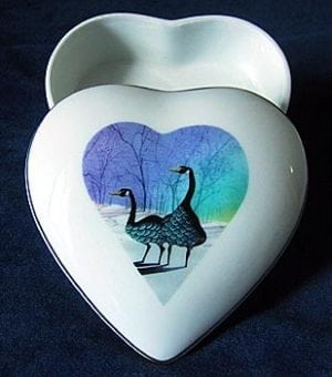 Geese Heart Shaped Porcelain Keepsake Box by P Buckley Moss. Two geese in heart-shaped background in purple and turquoise on a white box.