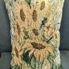 Golden sunflowers adorn this vertical pillow. Muted golden sunflowers with multicolored greenery.