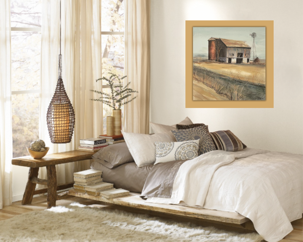 Cozy bedroom with a low wood bed, layered neutral bedding, woven pendant light, books on a bench, and framed barn artwork on the wall.